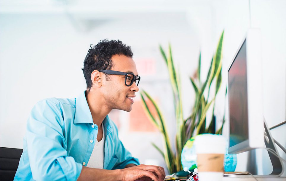 a man in glasses looking at a desktop computer monitor.