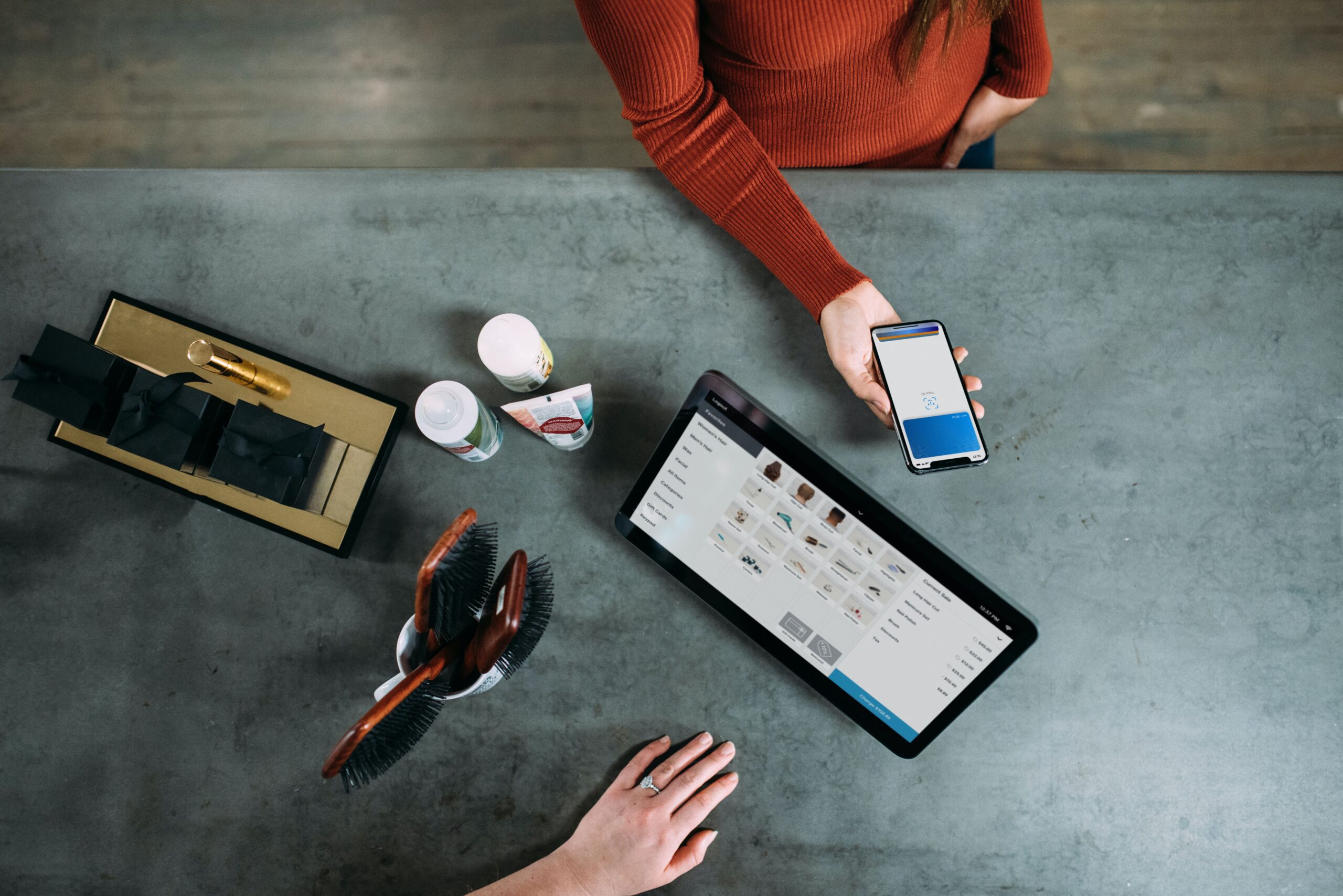 person holding their smartphone beside a tablet POS system.