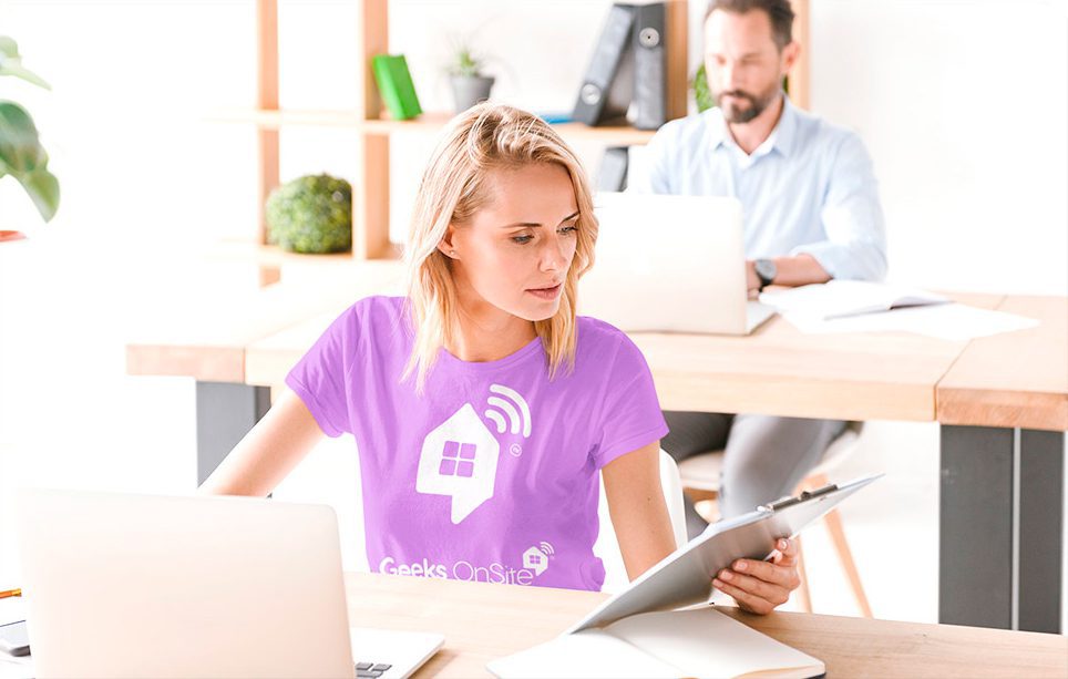 a woman in a purple shirt sitting at a desk with a laptop.